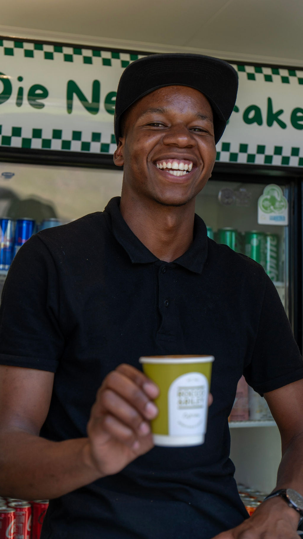 Smiling barista holding a Rocco & Riley coffee